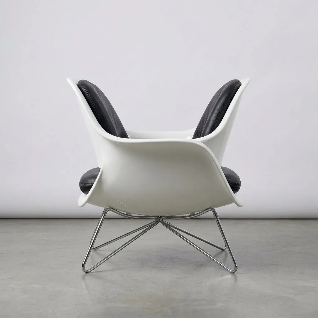 The same lounge seat from behind, showing the white moulded shell and the chrome wire legs